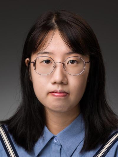 Headshot of Yutian in a blue shirt, wearing glasses, over a gray backdrop