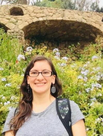 Magda smiling in front of a clover-covered hillside